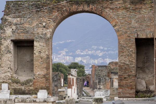 Tourists walk inside the Pompeii archaeological site in southern Italy, Tuesday, Feb. 15, 2022. In a few horrible hours, Pompeii went from being a vibrant city to a dead one, smothered by a furious volcanic eruption in 79 AD. Then in this century, Pompeii appeared alarmingly on the precipice of a second death, assailed by decades of neglect, mismanagement and scanty systematic maintenance of heavily visited ruins. (AP Photo/Gregorio Borgia)