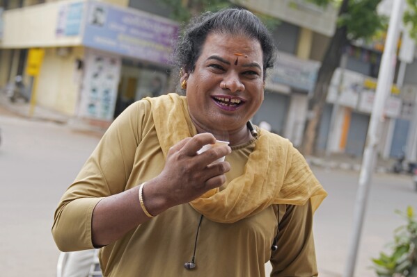 Preethi, a 38-year-old transgender woman who uses only her first name, drinks tea as she takes a break between ferrying passengers in her electric auto rickshaw in Bengaluru, India, Monday, July 10, 2023. She's now one of millions of electric vehicle owners in India, but one of very few to have received an EV through a charitable donation. (AP Photo/Aijaz Rahi)