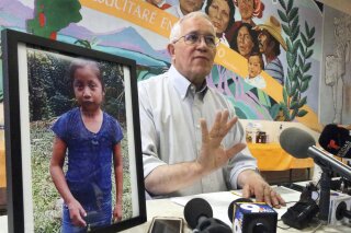 FILE - In this Dec. 15, 2018, file photo, Annunciation House director Ruben Garcia answers questions from the media after reading a statement from the family of Jakelin Caal Maquin, pictured at left, during a press briefing at Casa Vides in downtown El Paso, Texas. An autopsy has found that the 7-year-old girl from Guatemala who was detained by the U.S. Border Patrol died of a bacterial infection. Jakelin died on Dec. 8, just over a day after she was apprehended by Border Patrol agents with her father. (Rudy Gutierrez/The El Paso Times via AP, File)