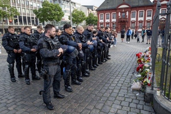 FILE - German police officers commemorate a colleague in Mannheim Germany, after learning that a police officer, who was stabbed two days ago there has died on Sunday, June 2, 2024. German authorities say they now see evidence of an Islamic extremist motive in last week's knife attack in the southwestern city of Mannheim in which a police officer was fatally injured. (AP Photo/Michael Probst, File)