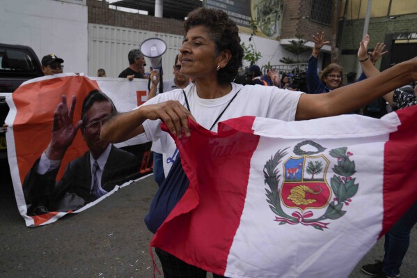 Supporters of jailed president Alberto Fujimori dance outside the prison where he is interned in the outskirts of Lima, Peru, Tuesday, Dec. 5, 2023. Peru's constitutional court ordered an immediate humanitarian release for the imprisoned former President who was serving a 25-year sentence in connection with the death squad slayings of 25 Peruvians in the 1990s. (AP Photo/Martin Mejia)