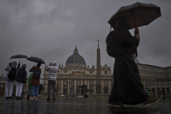 Tourists and locals walk in St. Peter's Square on a rainy day at the Vatican, Wednesday, March 12, 2025. (AP Photo/Francisco Seco)