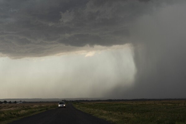 A car moves away from an approaching storm with a rain shaft during a Project ICECHIP operation on Tuesday, June 3, 2025, near Tipton, Okla. (AP Photo/Carolyn Kaster)