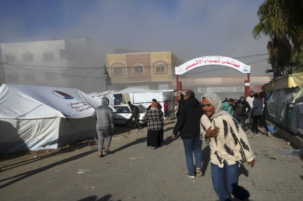 Palestinians run on the Al-Aqsa Hospital grounds moments after an Israeli strike hit a building next to it, in Deir al Balah, Gaza Strip, on Wednesday, Jan 10, 2023. (AP Photo/Adel Hana)