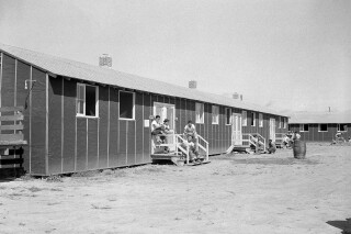 FILE - Relocated Japanese Americans sit on small front porches at barracks at Rohwer Relocation Center near Rohwer, Ark., on Sept. 21, 1942. Social media users are falsely claiming that the executive order authorizing Japanese incarceration during World War II provides recent migrants to the U.S. with gift cards. (AP Photo/Horace Cort, File)