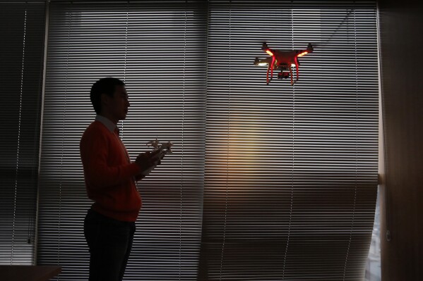 FILE - A staff member from DJI Technology Co. demonstrates the remote flying with his Phantom 2 Vision+ drone inside his office in Shenzhen, south China's Guangdong province, on Dec. 15, 2014. China imposed restrictions Monday, July 31, 2023 on exports of long-range civilian drones, citing Russia's war in Ukraine and concern that drones might be converted to military use. (AP Photo/Kin Cheung, File)