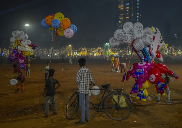 A group of balloon sellers wait for customers at the park during Diwali, the Hindu festival of lights, in Mumbai, India, Sunday, Nov. 12, 2023. (AP Photo/Rafiq Maqbool)