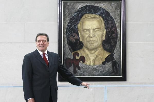 FILE - Former German Chancellor Gerhard Schroeder poses in front of a painting by German artist Joerg Immendorff in the chancellery in Berlin on Tuesday, July 10, 2007. Germany's three governing parties plan to strip former Chancellor Gerhard Schroeder of his office and staff after he maintained and defended his long-standing ties with Russia despite the war in Ukraine. (AP Photo/Markus Schreiber, File)