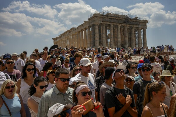Atop the Acropolis ancient hill, tourists visit the Parthenon temple, background, in Athens, Greece, Tuesday, July 4, 2023. Crowds are packing the Colosseum, the Louvre, the Acropolis and other major attractions as tourism exceeds 2019 records in some of Europe’s most popular destinations. While European tourists helped the industry on the road to recovery last year, the upswing this summer is led largely by Americans, who are lifted by a strong dollar and in some cases pandemic savings. (AP Photo/Thanassis Stavrakis)