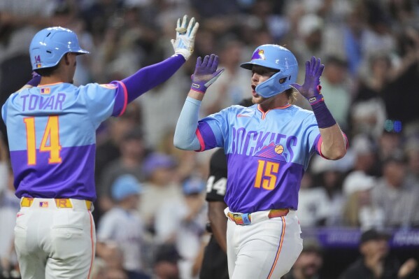 Colorado Rockies' Ezequiel Tovar, left, celebrates with Hunter Goodman, right, after they scored on a double hit by Ryan McMahon off New York Yankees relief pitcher Tim Hill in the fifth inning of a baseball game Friday, May 23, 2025, in Denver. (AP Photo/David Zalubowski)
