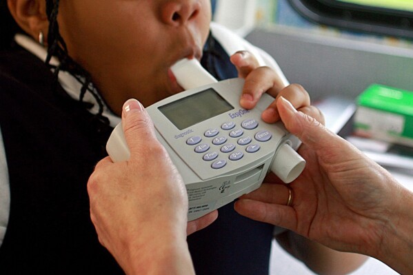 FILE - An 8-year-old student blows into a spirometer held by a nurse outside an elementary school in Bel Nor, Mo., in May 2009. The Doris Duke Charitable Foundation is awarding more than $10 million to five health organizations to reconsider the use of race in medical algorithms, which research shows can lead to potentially dangerous results for patients of color. (Christian Gooden/St. Louis Post-Dispatch via AP, File)