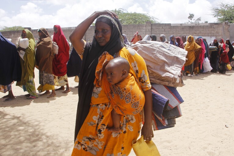 A woman, who fled amid a drought, carries her baby at a makeshift camo for displaced people on the outskirts of Mogadishu, Somalia on Tuesday, Sept. 26, 2023. (AP Photo/Farah Abdi Warsameh)