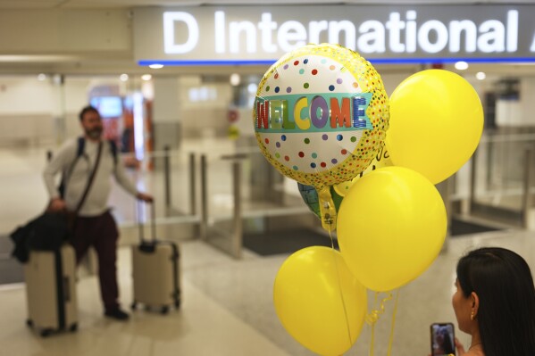 A woman holds balloons as passengers arrive from international flights, at Miami International Airport, Monday, June 9, 2025, in Miami. (AP Photo/Rebecca Blackwell)