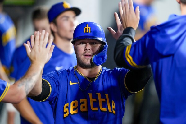 Seattle Mariners' Ty France is greeted in the dugout after scoring on a single by Mike Ford during the seventh inning of a baseball game against the Toronto Blue Jays, Friday, July 21, 2023, in Seattle. (AP Photo/Lindsey Wasson)