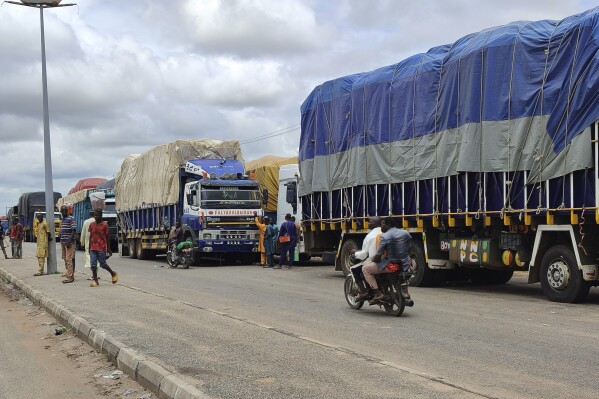 Stranded trucks with goods are seen at the border between Nigeria and Niger in Jibia, Nigeria, Monday, Aug. 7, 2023. The West Africa regional bloc's decision to shut borders with Niger in sanctioning the country's coup plotters is affecting businesses and locals in Nigerian towns where economic activities with Nigeriens had boomed for years. (AP Photo/Mohammed Babangida)