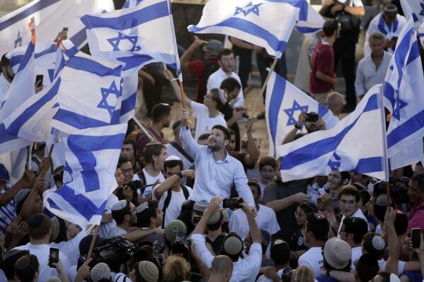 Israeli Knesset members Bezalel Smotrich, center, waves an Israeli flag together with other Jewish ultranationalists during the "Flags March" next to Damascus gate, outside Jerusalem's Old City, Tuesday, June 15, 2021. (AP Photo/Mahmoud Illean)