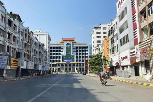 A man rides a motorbike on an empty street near a railway station Friday, Dec. 10, 2021, in Mandalay, central Myanmar. Streets were seen empty in Mandalay Friday as people participated in a "silent strike" to mark International Human Rights Day. Many offices, shops and restaurants were closed and people stayed indoors in protest of the military takeover. (AP Photo)