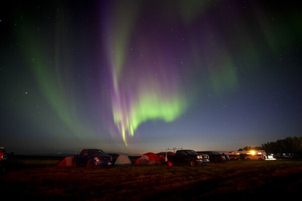 Evacuees from Yellowknife, territorial capital of the Northwest Territories, are greeted with the Aurora Borealis as they arrive to a free campsite provided by the community in High Level, Alta., Friday, Aug. 18, 2023. (Jason Franson /The Canadian Press via AP)