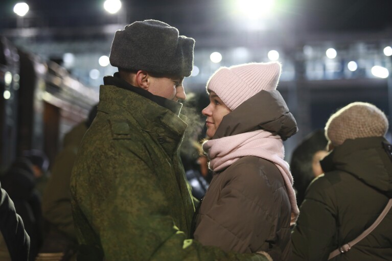 FILE - A couple embrace as other soldiers recently mobilized by Russia for service in Ukraine stand at a ceremony before boarding a train at a railway station in Tyumen, Russia, on Friday, Dec. 2, 2022. Hefty payments to hundreds of thousands of men who signed military contracts have helped boost consumer demand, contributing to economic growth. (AP Photo, File)