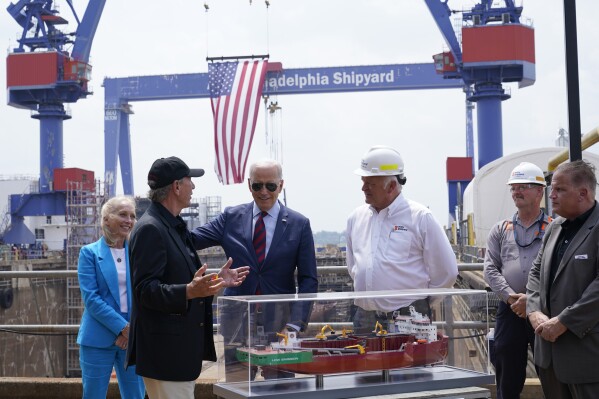 President Joe Biden talks with Lasse Petterson, CEO of Great Lakes Dredge and Dock, second from left, as he tours a shipyard in Philadelphia, Thursday, July 20, 2023. Rep. Mary Gay Scanlon, D-Pa., left, and Steinar Nerbovik, CEO of Philadelphia Shipyard, Inc., third from right, look on. (AP Photo/Susan Walsh)