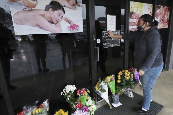 Jessica Lang pauses and places her hand on the door in a moment of grief after dropping off flowers at Youngs Asian Massage parlor where four people were killed, Wednesday, March 17, 2021, in Acworth, Ga. Lang, a local resident who lives nearby, said she knew one of the victims. A white gunman was charged Wednesday with killing eight people at three Atlanta-area massage parlors on Tuesday in an attack that sent terror through the Asian American community that’s increasingly been targeted during the coronavirus pandemic. (Curtis Compton/Atlanta Journal-Constitution via AP)