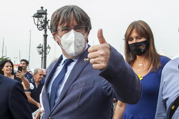 Catalan separatist leader Carles Puigdemont, left, gives thumbs up as he walks with the Speaker of the Catalan Parliament Laura Borras in Alghero, Sardinia, Italy, Saturday, Sept. 25, 2021. Puigdemont took a leisurely walk in the Sardinian city, waving to supporters, a day after a judge freed him from jail pending a hearing on his extradition to Spain, where the political firebrand is wanted for sedition. (AP Photo/Francesca Salaris)