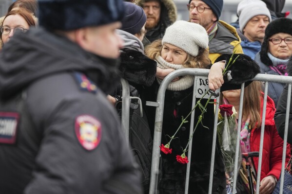 A Police officer guards as people gather near the Church of the Icon of the Mother of God Soothe My Sorrows, in Moscow, Russia, Friday, March 1, 2024. Relatives and supporters of Alexei Navalny are bidding farewell to the opposition leader at a funeral in southeastern Moscow, following a battle with authorities over the release of his body after his still-unexplained death in an Arctic penal colony. (AP Photo)