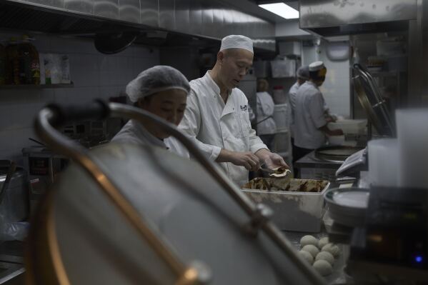 Feng Yong, center, makes meat pie with his staff at a muslim restaurant offering the "aixincan” or “loving meals," in Beijing on March 18, 2025. (AP Photo/Andy Wong)