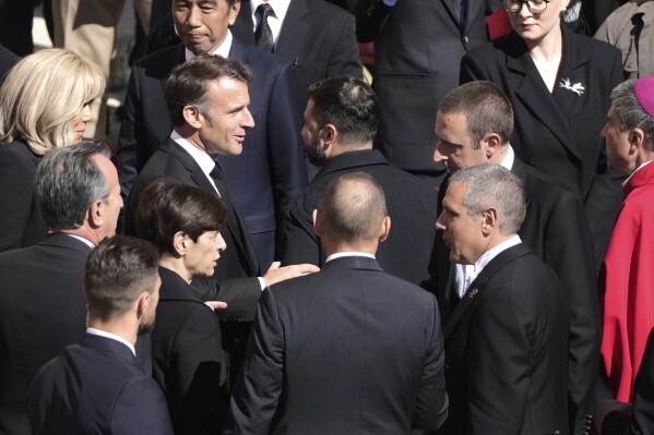 El presidente francés Emmanuel Macron, centro-izquierda, habla con el mandatario ucraniano Volodymr Zelenskyy, centro-derecha, tras su llegada al funeral del papa Francisco en la Plaza de San Pedro, el sábado 26 de abril de 2025. (AP Foto/Markus Schreiber)