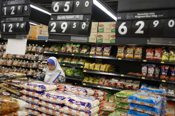 FILE - A Malaysian Muslim woman checks on rice grain in a mall outside Kuala Lumpur, Malaysia on Aug. 18, 2015. Malaysia's government said Monday, Oct. 2, 2023, the country that enough rice is available and urged people not to hoard locally produced rice after recent panic-buying led to empty shelves in supermarkets and grocery stores nationwide. (AP Photo/Joshua Paul, File)