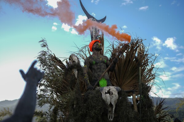 A reveler holds a tiki torch shooting out red smoke during a Mud Block carnival party in Paraty, Brazil, Saturday, March 1, 2025. (AP Photo/Andre Penner)