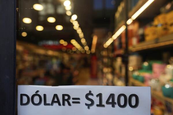 A sign displays the exchange rate between the U.S. dollar and the Argentine peso that is used at a store in Buenos Aires, Argentina, Monday, April 14, 2025. (AP Photo/Natacha Pisarenko)