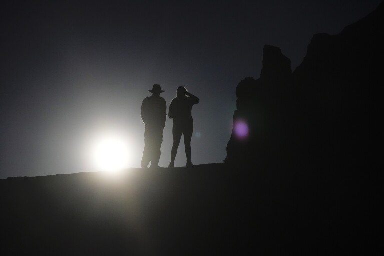 People watch the sun rise over Bryce Canyon National Park, Utah, before a rare "ring of fire" eclipse of the sun Saturday, Oct. 14, 2023. (AP Photo/Rick Bowmer)