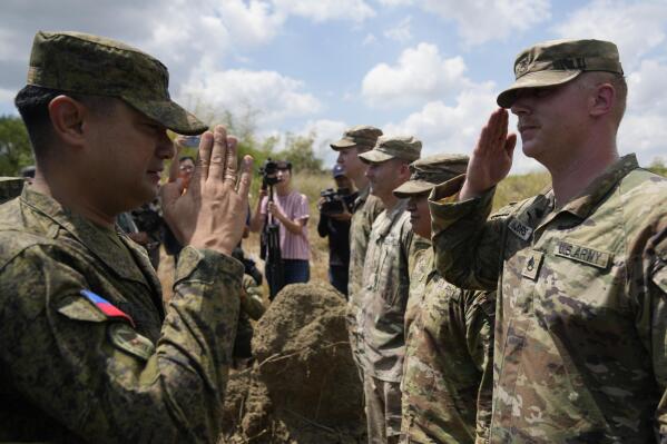 Philippine Army Artillery Regiment Commander Anthony Coronel, left, returns a salute from a US soldier during a joint military drill called Salaknib at Laur, Nueva Ecija province, northern Philippines on Friday, March 31, 2023. The U.S. and the Philippines have agreed to hold more small and major combat exercises in 2023 and expand annual military drills following disruptions caused by two years of coronavirus lockdowns, according to Philippine military officials. (AP Photo/Aaron Favila)