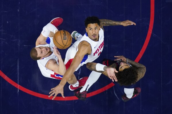 From left, Detroit Pistons' Malachi Flynn, Jared Rhoden and Philadelphia 76ers' Kelly Oubre Jr. reach for a loose ball during the second half of an NBA basketball game, Tuesday, April 9, 2024, in Philadelphia. (AP Photo/Derik Hamilton)