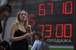 FILE - A woman walks past an exchange office screen showing the currency exchange rates of U.S. Dollar to Russian Rubles in St. Petersburg, Russia, Tuesday, July 5, 2022. Russia’s gross domestic product contracted 4% in the second quarter of this year, the state statistical service said Friday, Aug. 12. (AP Photo/Dmitri Lovetsky, File)