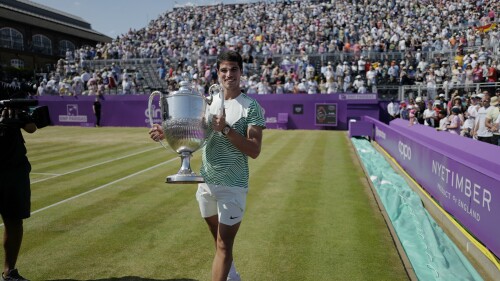 Carlos Alcaraz, of Spain, carries the trophy after defeating Alex de Minaur, of Australia, 6/4, 6/4 in the mens singles final match at the Queens Club tennis tournament in London, Sunday, June 25, 2023. (AP Photo/Alberto Pezzali)