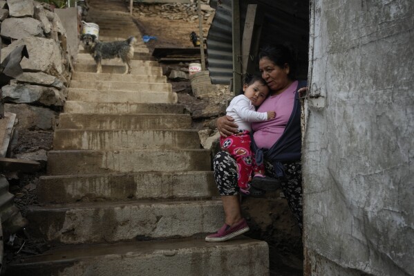 Justina Flores holds her grandchild Maria Paz while resting in the entrance of her home in the Pamplona Alta area in Lima, Peru, Friday, March 8, 2024. (AP Photo/Martin Mejia)