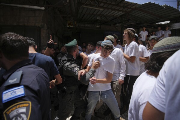 Israeli police scuffle with Israeli youths during a march marking Jerusalem Day, an Israeli holiday celebrating the capture of east Jerusalem in the 1967 Mideast war, in Jerusalem's Old City, Monday, May 26, 2025. (AP Photo/Ohad Zwigenberg)