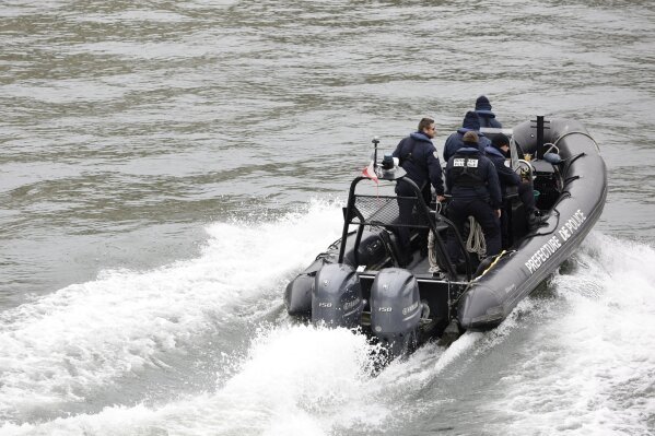 Police officers patrol in a rubber boat on the Seine river after an incident at the police headquarters in Paris, Thursday, Oct. 3, 2019. A French police union official says an attacker armed with a knife has killed one officer inside Paris police headquarters before he was shot and killed. (AP Photo/Kamil Zihnioglu)