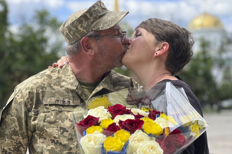 Olena Yahupova kisses her husband, Arthur Yahupov on the day of their wedding ceremony in Kharkiv, Ukraine, on June 7, 2023. After escaping detention by Russian soldiers, she traveled thousands of miles through Russia, north to the Baltics and back around to the frontline in Ukraine, where she reunited with her husband serving with Ukrainian forces. Earlier married in a civil ceremony, the two got wed in church. (AP Photo/Oleksandr Brynza)