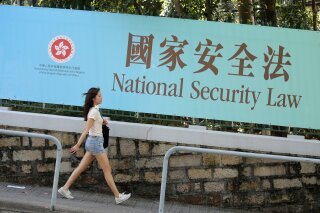 A woman walks past a promotional banner of the national security law for Hong Kong, in Hong Kong, Tuesday, June 30, 2020. China has approved a contentious law that would allow authorities to crack down on subversive and secessionist activity in Hong Kong, sparking fears that it would be used to curb opposition voices in the semi-autonomous territory. (AP Photo/Kin Cheung)