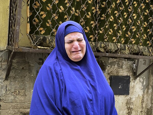 In this April 17, 2020 photo, Umm Gouda, a close friend of 73-year-old Ghaliya Abdel-Wahab who died from COVID-19 on April 6, 2020, weeps as she talks about her near her home, on one of two streets on complete lockdown closed off by security forces for people to quarantine after her death, in Bahtim, Shubra el-Kheima neighborhood, Qalyoubiya governorate, Egypt. (AP Photo/Nariman El-Mofty)
