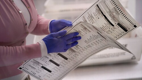 FILE - An election worker carries two ballots to be verified inside the Maricopa County Recorders Office, Nov. 10, 2022, in Phoenix. Few Republicans have high confidence that votes will be tallied accurately in next year’s presidential contest, suggesting years of sustained attacks against elections by former President Donald Trump and his allies have taken a toll. A new poll from The Associated Press-NORC Center for Public Affairs Research shows that just 22% of Republicans have high confidence in the 2024 vote count compared to 71% of Democrats. (AP Photo/Matt York, File)