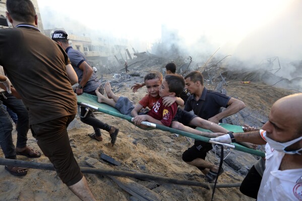 Palestinians evacuate two wounded boys out of the destruction following Israeli airstrikes on Gaza City, Wednesday, Oct. 25, 2023. (AP Photo/Abed Khaled)
