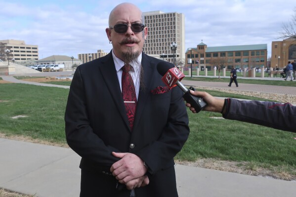 Michael Stewart, the President of the Kansas City-area Satanic Grotto, speaks with reporters as the group's rally gets started outside the Kansas Statehouse, Friday, March 28, 2025, in Topeka, Kansas. (AP Photo/John Hanna)
