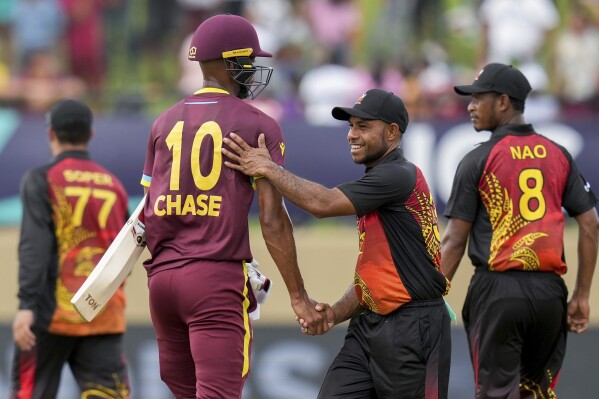 Papua New Guinea's Sese Bau congratulates West Indies' batsman Roston Chase after their ICC Men's T20 World Cup cricket match at Guyana National Stadium in Providence, Guyana, Sunday, June 2, 2024. (AP Photo/Ramon Espinosa)