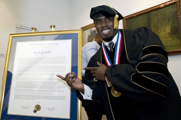 FILE - Entertainer and entrepreneur Sean Combs poses next to his honorary degree of Doctor of Humanities during the graduation ceremony at Howard University in Washington, Saturday, May 10, 2014. In a decision, Friday, June 7, 2024, Howard University is cutting ties to Combs, rescinding the honorary degree that was awarded to him and disbanding a scholarship program in his name. (AP Photo/Jose Luis Magana, File)