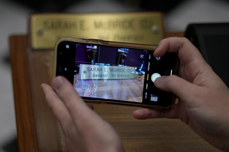 U.S.-Rep.-elect Sarah McBride, D-Del., photographs her desk nameplate on the Senate floor on her last day as a Delaware state senator at the Delaware Legislative Hall in Dover, Del., Monday, Dec. 16, 2024. (AP Photo/Carolyn Kaster)