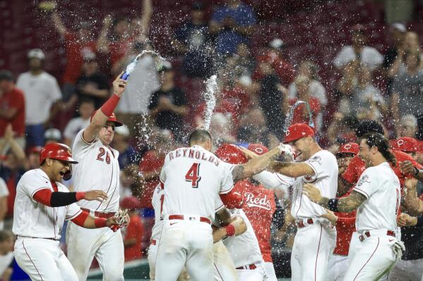 Cincinnati Reds' Mike Moustakas, middle, celebrates with teammates after hitting an RBI sacrifice fly during the ninth inning of the team's baseball game against the New York Mets in Cincinnati, Tuesday, July 5, 2022. The Reds won 1-0. (AP Photo/Aaron Doster)
